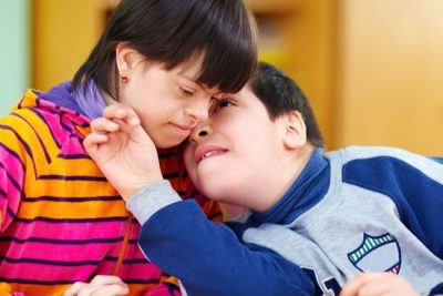 A girl and boy, both with Down Syndrome, talking at a table